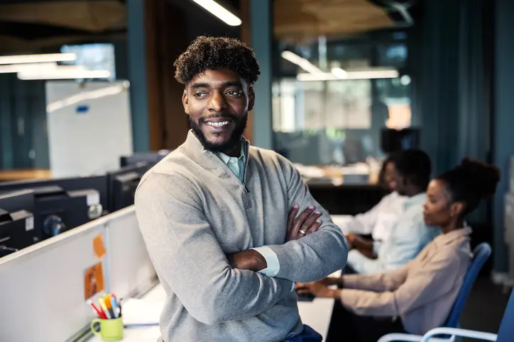 Smiling man standing in modern office workspace